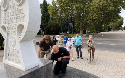 Люди несут цветы и игрушки к поклонному кресту в Краснодаре в память о погибших